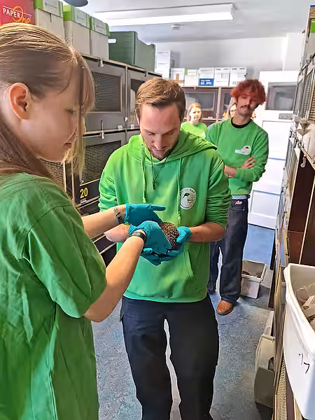 Die Tierpflegerin reicht dem Kollegen einen Igel.