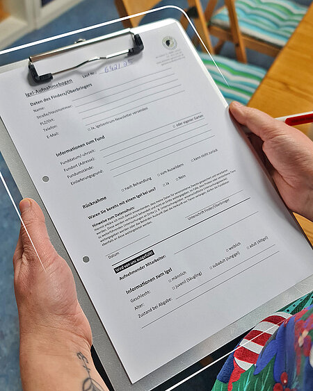 Zwei Hände halten ein Klemmbrett mit einem Dokument.