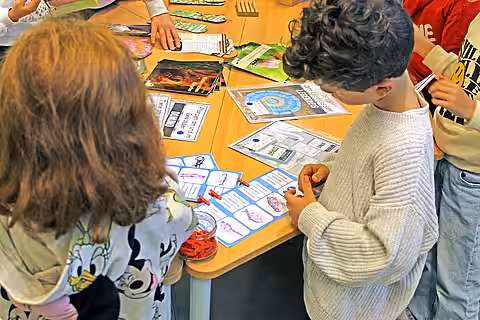 Eröffnung des Tierschutzzimmers in der Zinnowwald Grundschule in Berlin Zehlendorf Zwei Kinder schauen sich Lernmaterial auf einem Tisch an.