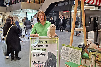 Eine Frau mit einem Aufsteller an einem Infostand